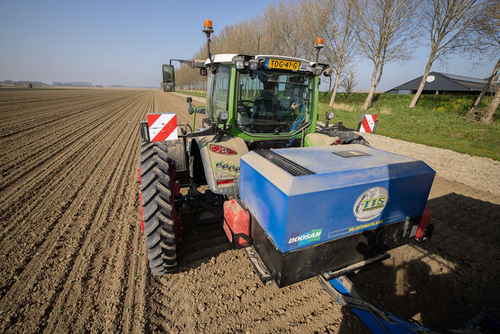 Trekker op 330 centimeter spoorbreedte. De box achterop de trekker bevat de compressor voor de aansturing van de plantrobots.