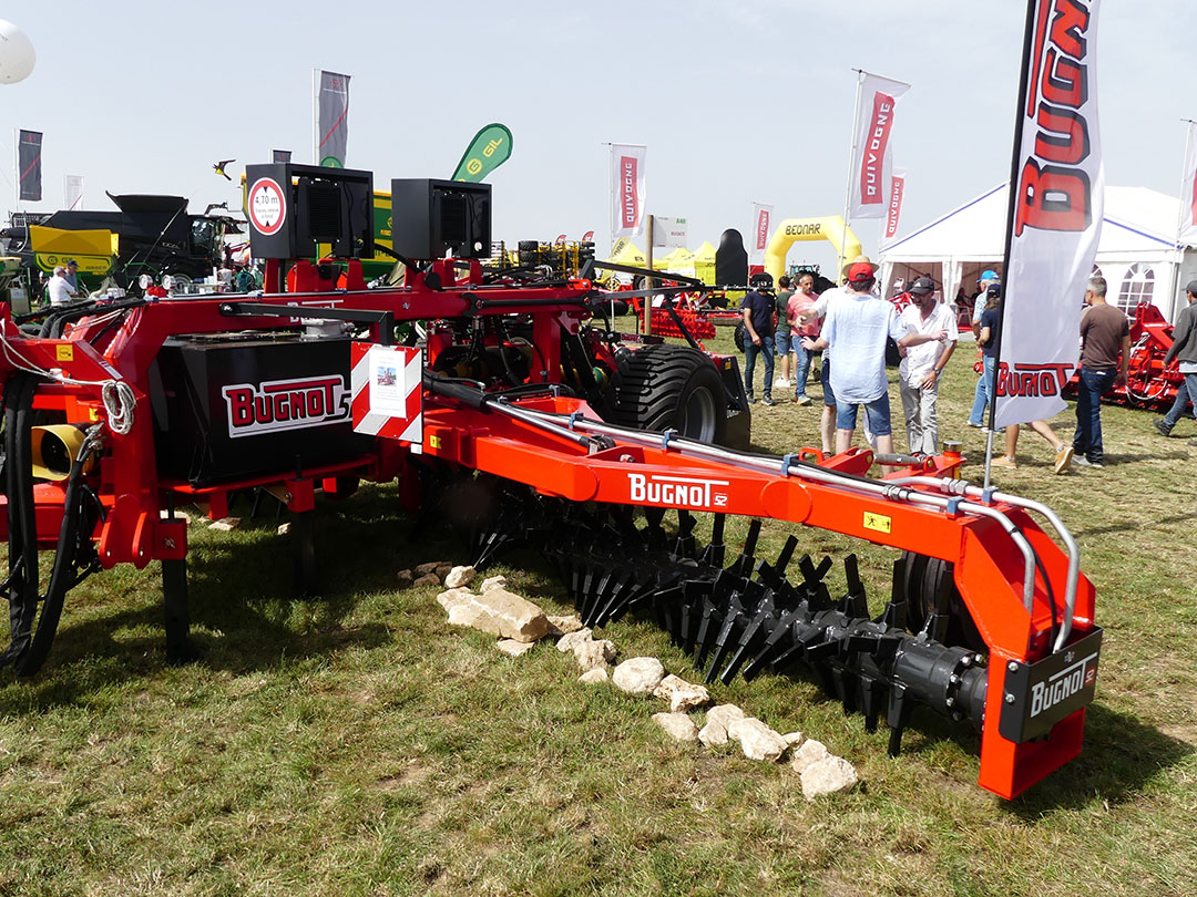 Bugnot is een Franse fabrikant die onder andere bekend is door zijn ecoploeg. De fabrikant maakt ook werktuigen voor de bosbouw. Dit jaar introduceert het een bijna 8 meter breed werkende stenenverzamelaar. Die legt de stenen in een zwad dat door een aangebouwde stenenbreker wordt verpulverd. De rotor is gebaseerd op een zware bosfrees. Bij 5 centimeter diep loskrabben en naar het midden werken van de stenen rekent Bugnot dat 200 pk noodzakelijk is, plus nog een keer 180 pk voor de stenenbreker.