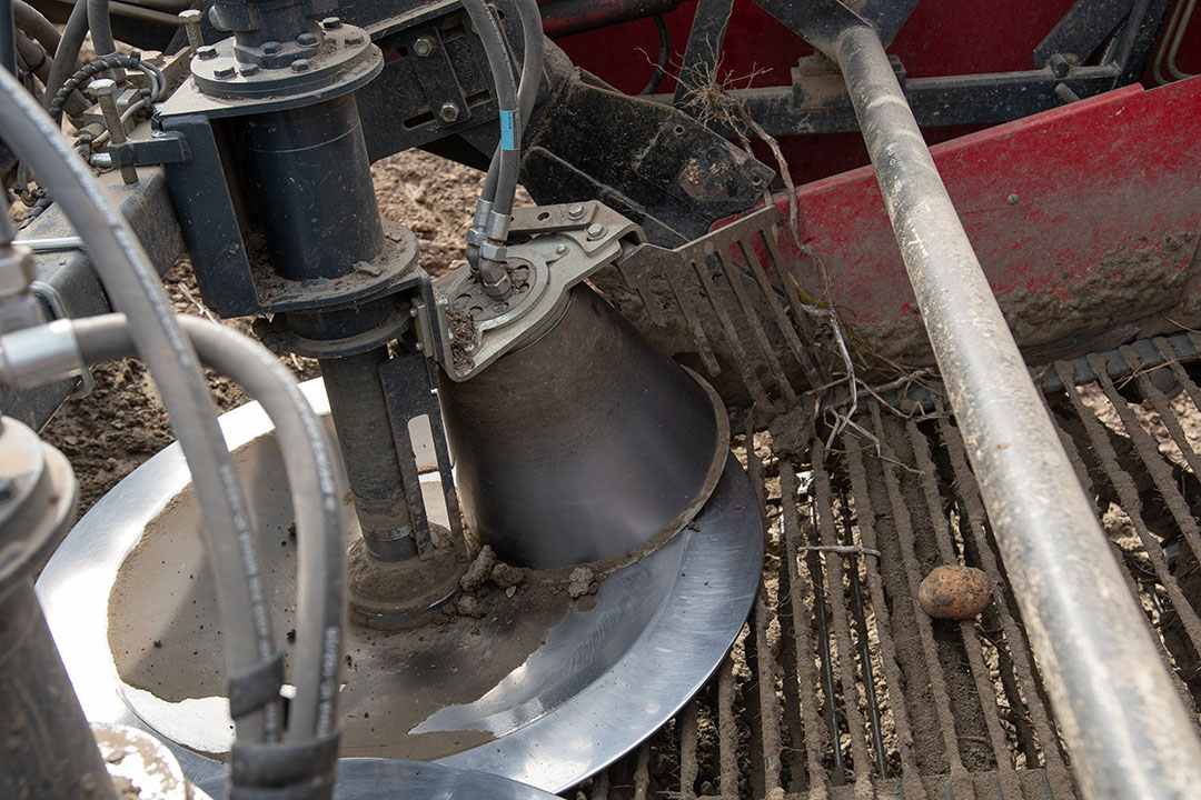 Een poetskegel bevordert de doorstroom door aardappels en grond op de rooimat te draaien. Ook poetst de kegel de holle binnenschijf schoon.