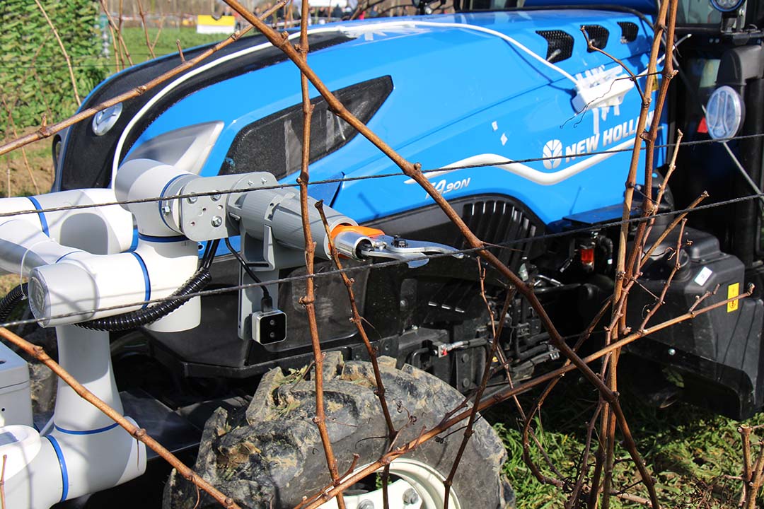 De robotarm met een elektrische snoeischaar werd voor een demonstratie op robotbeurs World Fira bevestigd aan de voorkant van een New Holland T4.90N-trekker.