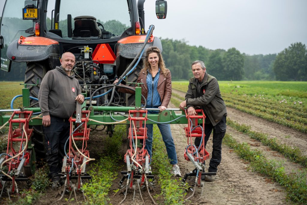 Rafal Zapart (links) werkt met de machine. In het midden staat Suzanne Verhaegh-Seuren (directie), en rechts staat Stan Seuren, de uitvinder van de persluchtschoffel.