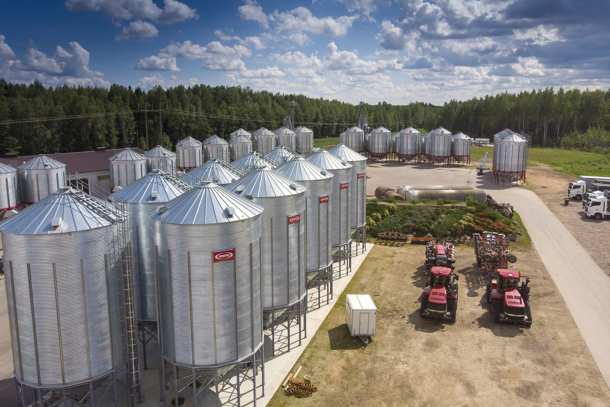 Vijftig glimmende graansilo’s staan op het erf van Z/S Kotiņi. De Letse zaaizaadproducent teelt evenveel soorten en rassen granen. De twee Amerikaanse Quadtrac-kniktrekkers vallen maar klein uit, naast de in totaal 14.000 ton graan opslag. Eigenaar Aldis Ločmelis zag zijn onderneming in ruim 30 jaar groeien van 14 naar 5.000 hectare. Het machinepark groeide mee.– Foto’s: Mark Pasveer