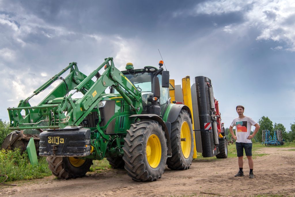 Rihard Lukins, eigenaar van Upeskalma Komplekss, een voormalige kolchoz, staat bij de meest recente combinatie van het bedrijf. Het is een John Deere 6250R met voorlader met erachter de eerste Pöttinger Mergento 9220 in Letland. – Foto’s: Mark Pasveer