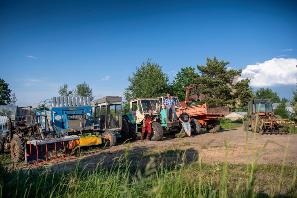 Jonas Chaladauskas (in het midden), links zijn zoon Andrius en rechts neef Donatas Stundzia poseren trots voor Jonas’ machinepark. Zoon Andrius is actief in de grond- en wegenbouwsector en sleutelt ook in de werkplaats bij Jonas. Neef Donatas hielp voorhien op de boerderij, maar werkt nu op een vliegveld.