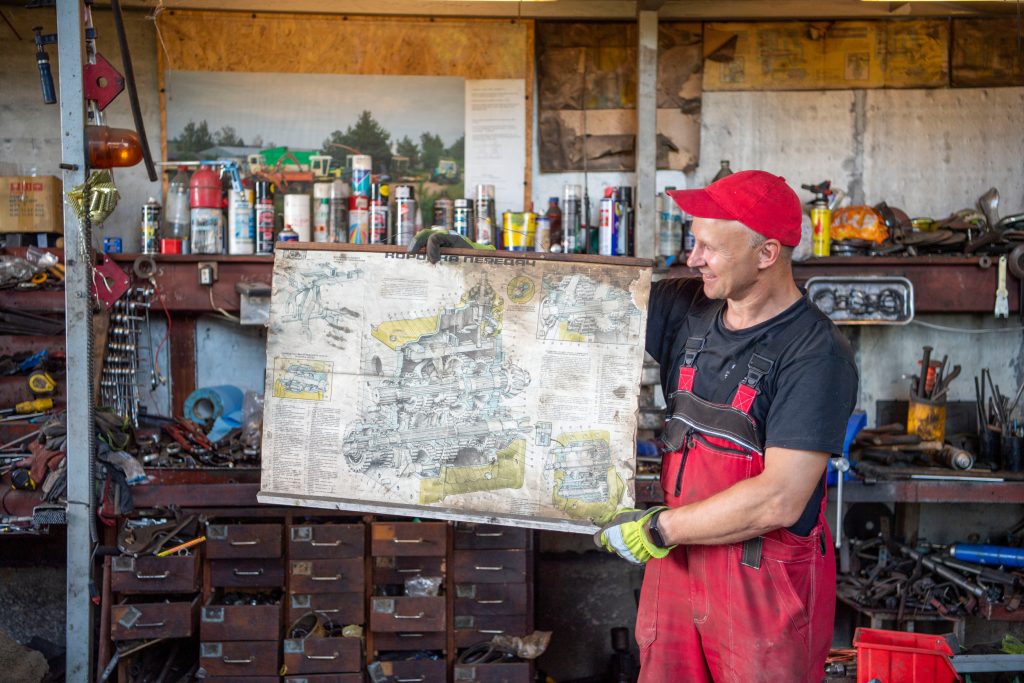 Andrias Chaladauskas toont een van de explosietekeningen van Zetor-motoren en -versnellingsbakken die aan de muur hangen.