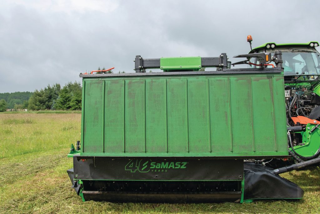 De banden zitten aan een koker geklemd, zodat je de zwadbreedte handmatig kunt aanpassen. Onder de kneuzers, tegen de achterkant van de messenbalk, zit een soort opvangbak. Die dient voor restjes die van de afvoerbandjes afvallen en gooit deze via de kneuzer opnieuw terug. Zonder de bandjes omlaag verzamelt dit onnodig gras en gooit dit op de grond. De Nederlandse importeur demonteert deze voor ons land.