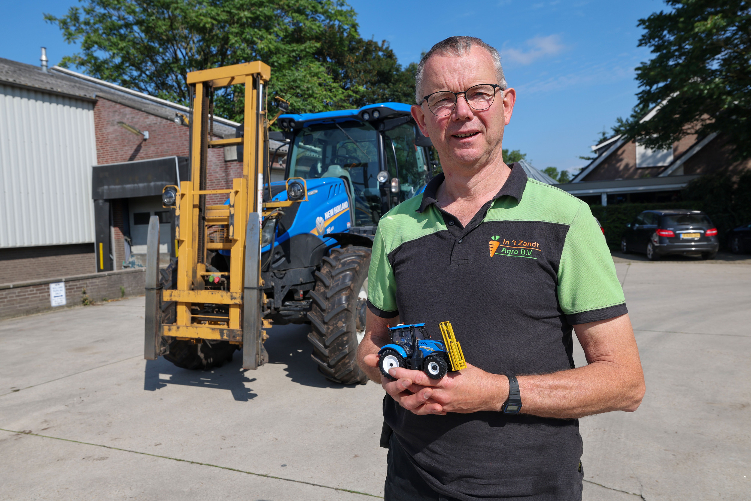 Huub in 't Zandt poseert met zijn miniatuur New Holland T6.165, met op de achtergrond de trekker in groot formaat. “Een collega-miniaturenverzamelaar bouwde dezelfde hefmast voor kuubskisten op die wij in het groot gebruiken. Ik heb de set cadeau gedaan aan de medewerkers, als kerstpakket.”– Foto: Bert Jansen