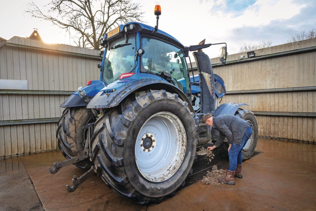 Bij een erg vervuilde trekker haal je met de hand de kluiten modder weg.