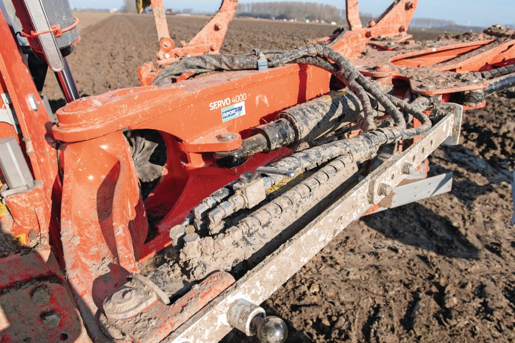 De zwenkconstructie is verlengd ten opzichte van het vorige model. Vanuit de cabine is de cilinder die daaraan vastzit van het ene aanslagpunt tot het andere uit te zwenken om van on land naar in de voor te gaan en andersom. Het kogelkraantje op de geheugencilinder in de voorgrond moet je sluiten bij bovenover ploegen.