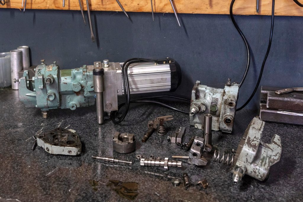 Hydraulische regelaars zochten de broers zelf op. De achterste zit aan een elektromotor om te testen. Ervoor eentje in onderdelen.