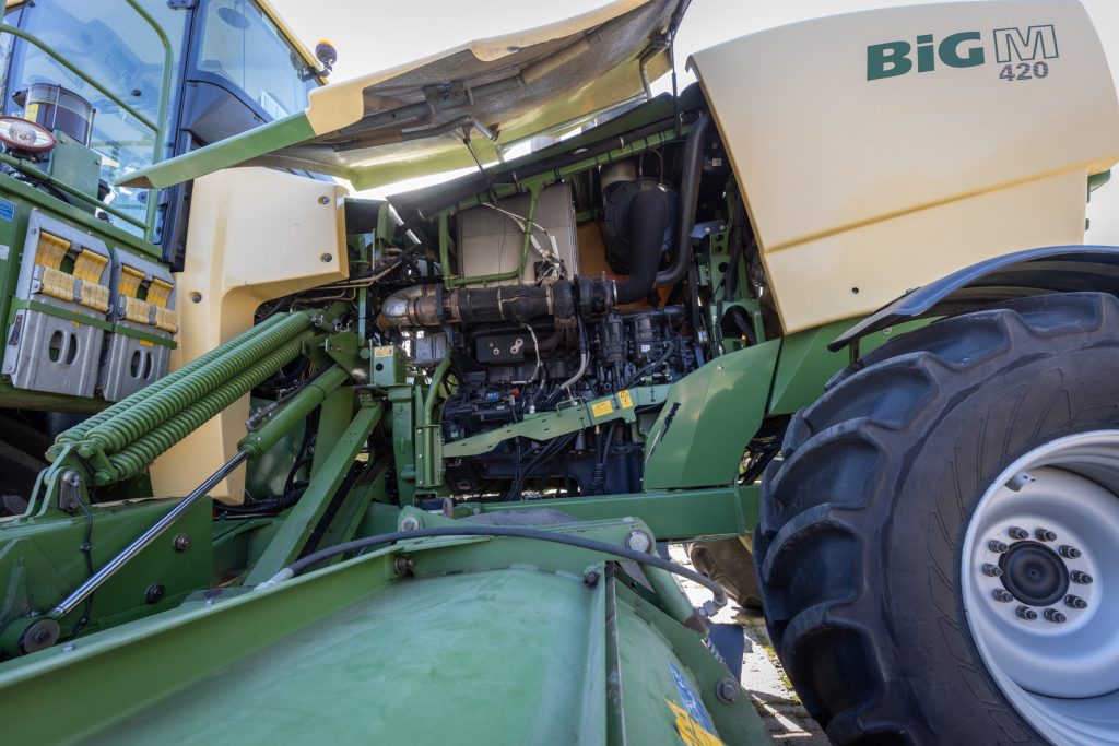 De dikke motor, die via een tandwielkast en powerband-aandrijving direct de maaiers aandrijft. Er zit een rubberen torsiedemperplaat tussen, die vanwege ouderdom kapot kan gaan. Dan kun je gelijk niets meer, want de hydrauliekpompen worden dan niet meer aangedreven. Daarom vervangen dealers deze preventief als dat nodig blijkt na inspectie.