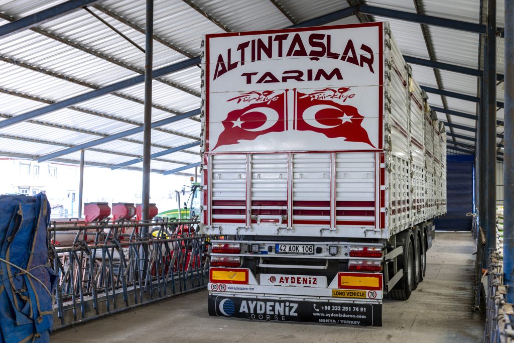 Een gloednieuwe drie-assige trailer, met fraaie stickers aan de achterkant. Geparkeerd op wat ooit een voergang was. Atlintaşlar Tarim doet het transportwerk zelf, en doet er ook loonwerk mee.