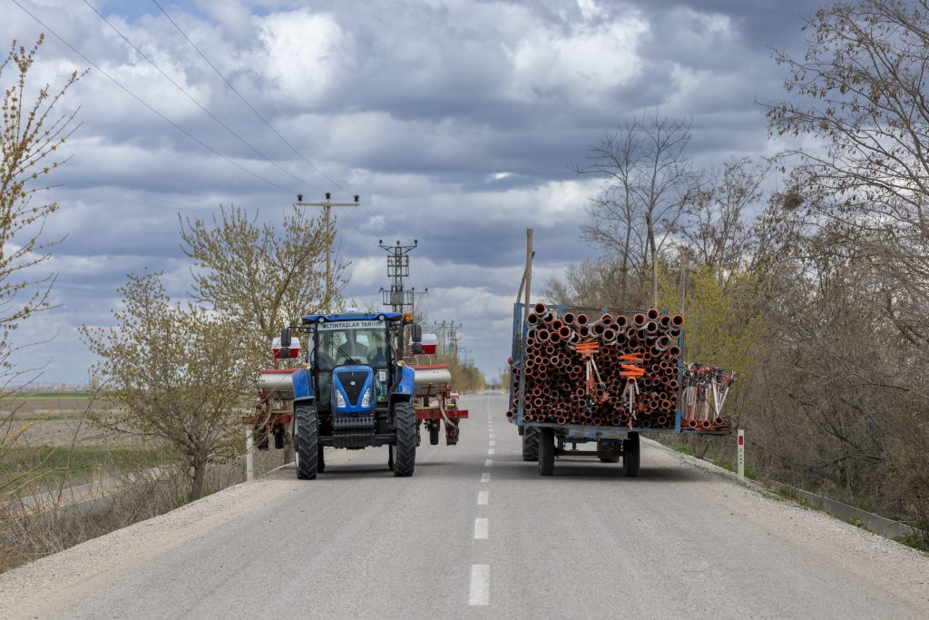 Even krap op de weg. Een New Holland TD100D met zaaimachine komt net terug, en een Massey Ferguson 285, gebouwd door het Turkse Uzel, verlaat het bedrijf met materiaal voor irrigatie.