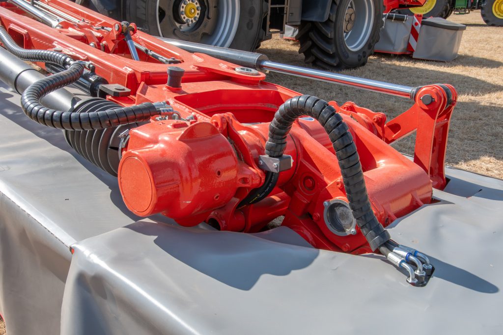 Hier de scharnierende tandwielkast in beeld. Schuin erboven het scharnier waarmee de balken in het midden kunnen knikken als er een obstakel in het midden voor de balk terechtkomt. Het kleine cilindertje aan de achterzijde trekt dan uit en stuurt olie naar het Liftcontrol-systeem, waardoor de draagarm iets tilt.