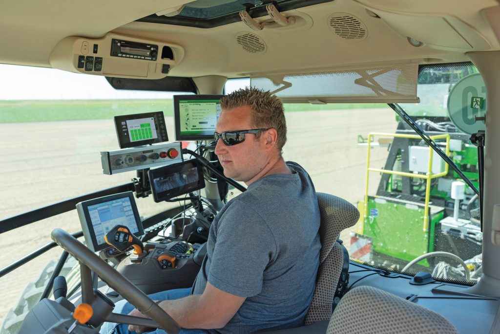 Vaste medewerker Koen Groeneveld aan boord van de John Deere 6R. Zowel op de trekker als op de plantmachine zit een gps-unit. Op het display is mooi te zien hoe de plantmachine af en toe zelfstandig kleine correcties maakt, en zo keurig recht blijft werken. De plantsnelheid is 3,4 kilometer per uur.