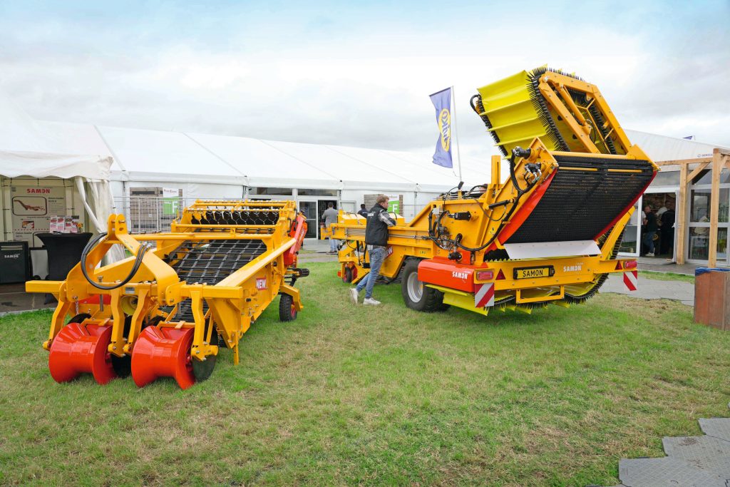 De nieuwe Samon-uienlader SU2L was onlangs te zien op vakbeurs PotatoEurope in Lelystad (Fl.). Links staat een zwadrooier voor aardappelen, die Samon nu ook met een doorvalmat levert.