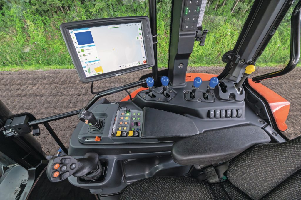 De zijconsole herbergt een kort versnellingspookje met functieknoppen voor onder andere powershift en hef, een klein kruishendeltje voor de voorlader/fronthef en diverse druk- en draaiknoppen. De ventielen worden nog met hendels bediend.