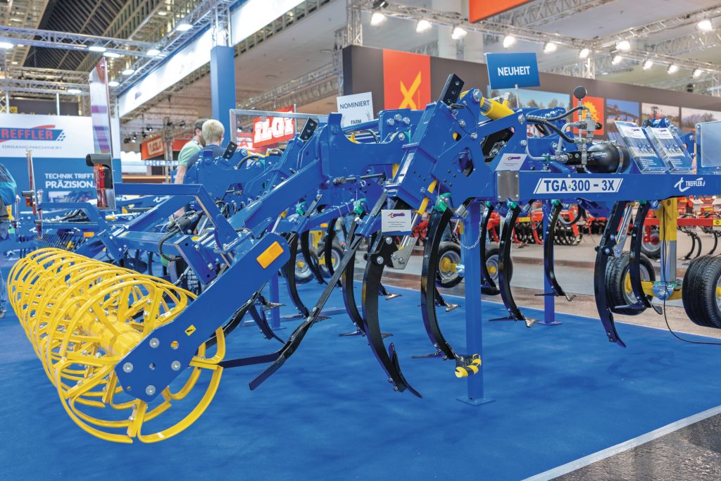 Topmodel is de 3X-variant van de TGAPlus-cultivator. Die is uit te rusten met woeltanden (smalle beitel) achter de cultivatortand met ganzevoet. Nauwkeurige ondiepe stoppelbewerking wordt dan gecombineerd met de mogelijkheid om sporen los te trekken. Als tweede tand kun je ook een zaaibuis monteren. De gele cilinder dient om desgewenst de woeltand uit te heffen.