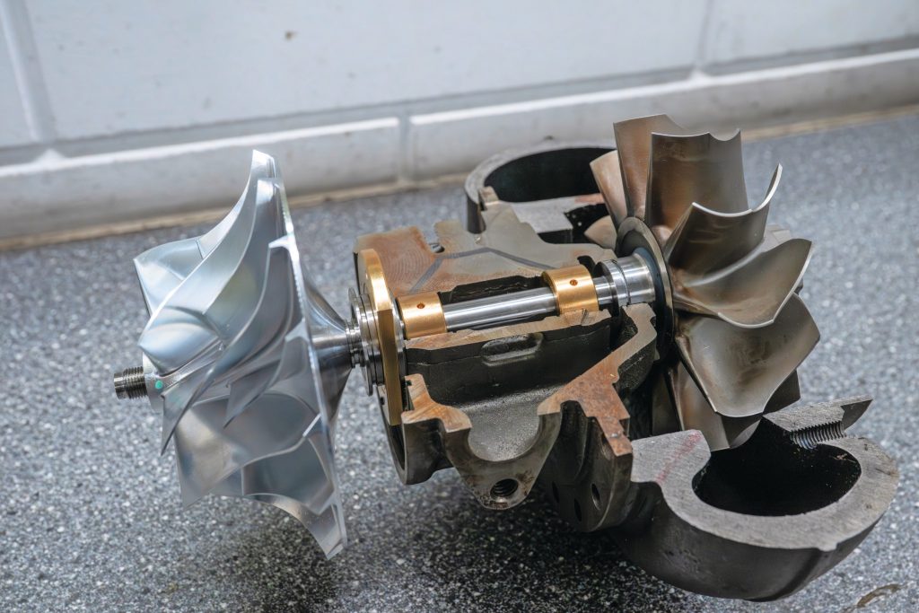 Een opengewerkte turbo zonder compressorhuis. Van links naar rechts een compressorwiel, axiaallager, lagerhuis met radiaallagers en turbinewiel.